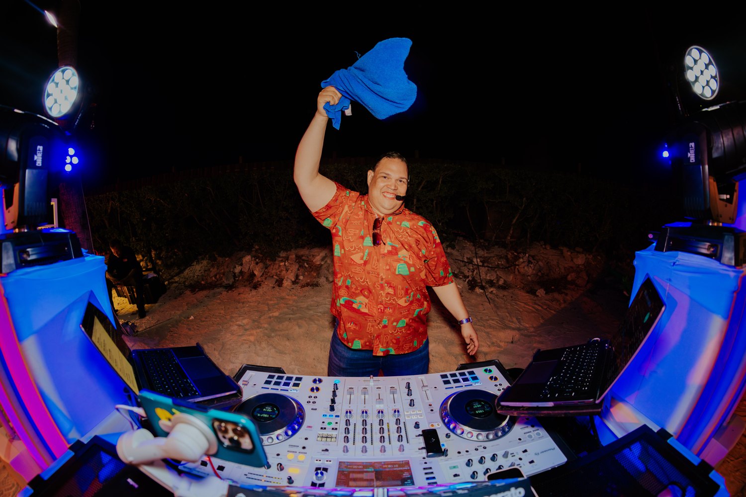 Ruuben raising a blue towel behind his DJ decks during a celebration.